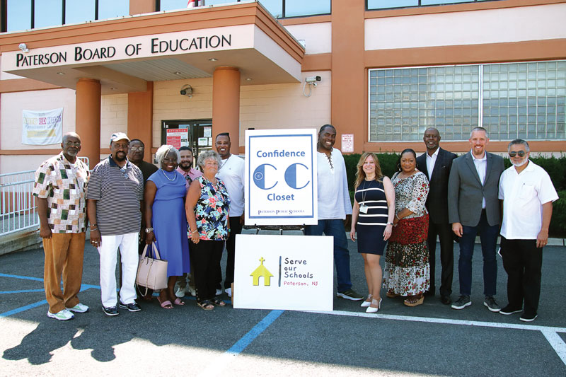 Eileen F. Shafer, superintendent of Paterson Public Schools, second from the left of the signs, and Norman S. Weir School Principal Grace Giglio, second from the right of the signs, with leaders of the Serve Our Schools coalition of Paterson churches at the launch of the Confidence Closets initiative last summer.