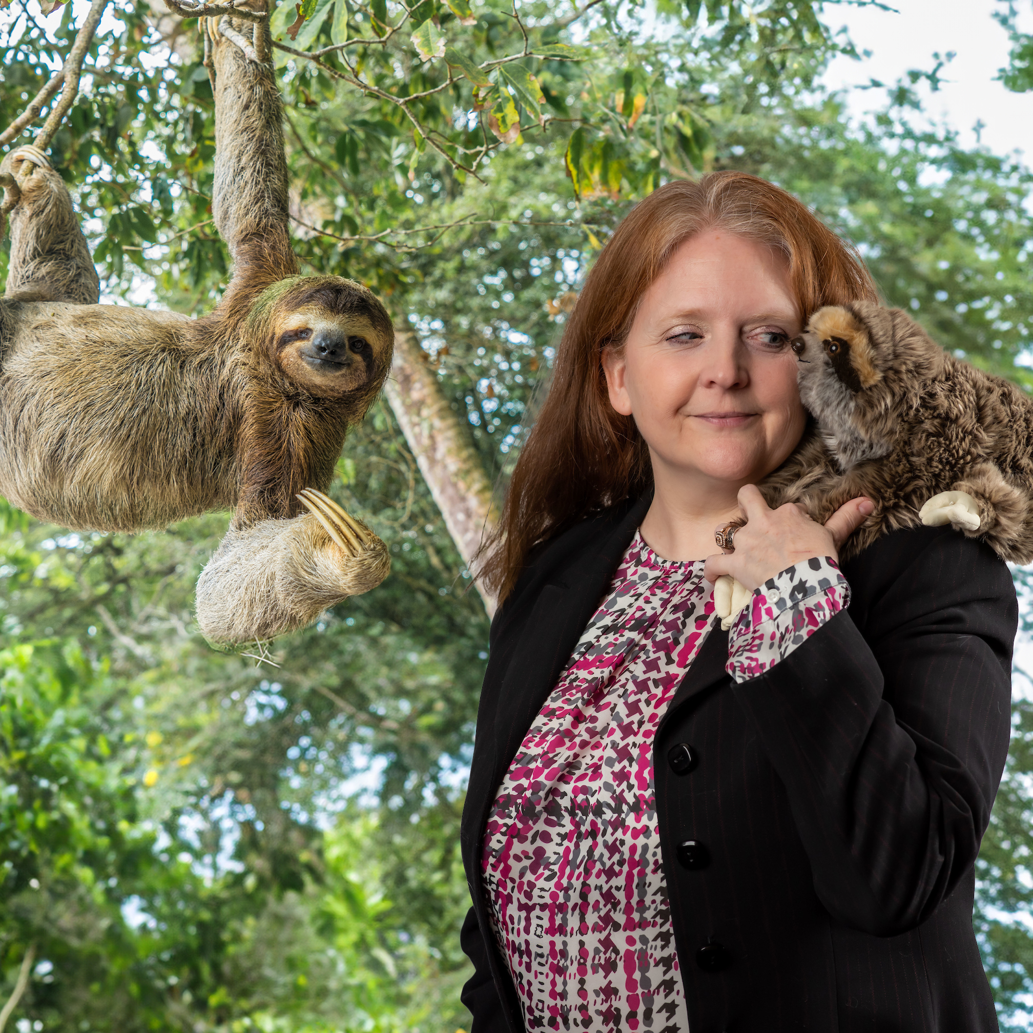 Kathleen Asher posing with sloths with trees