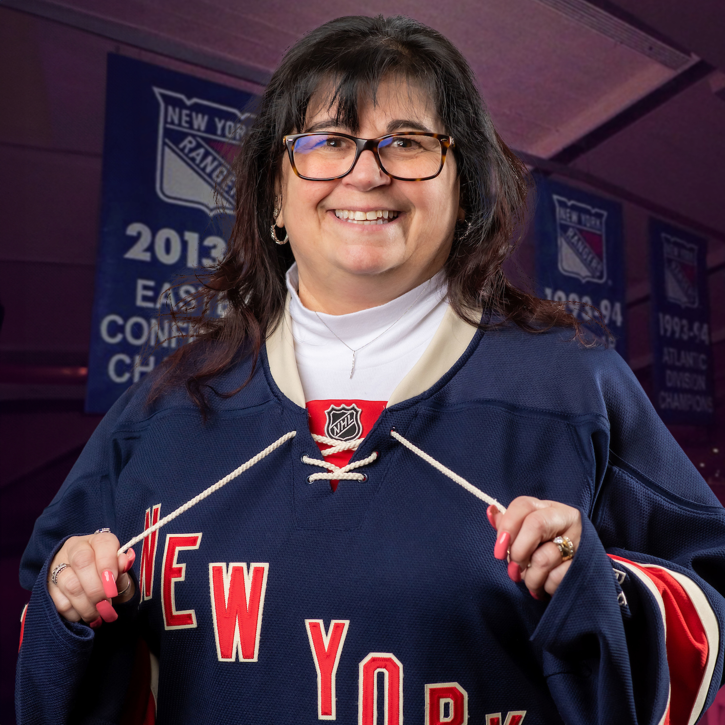 Gina Cuciti posing in a New York Rangers hockey jersey with their championship flags flying in the background