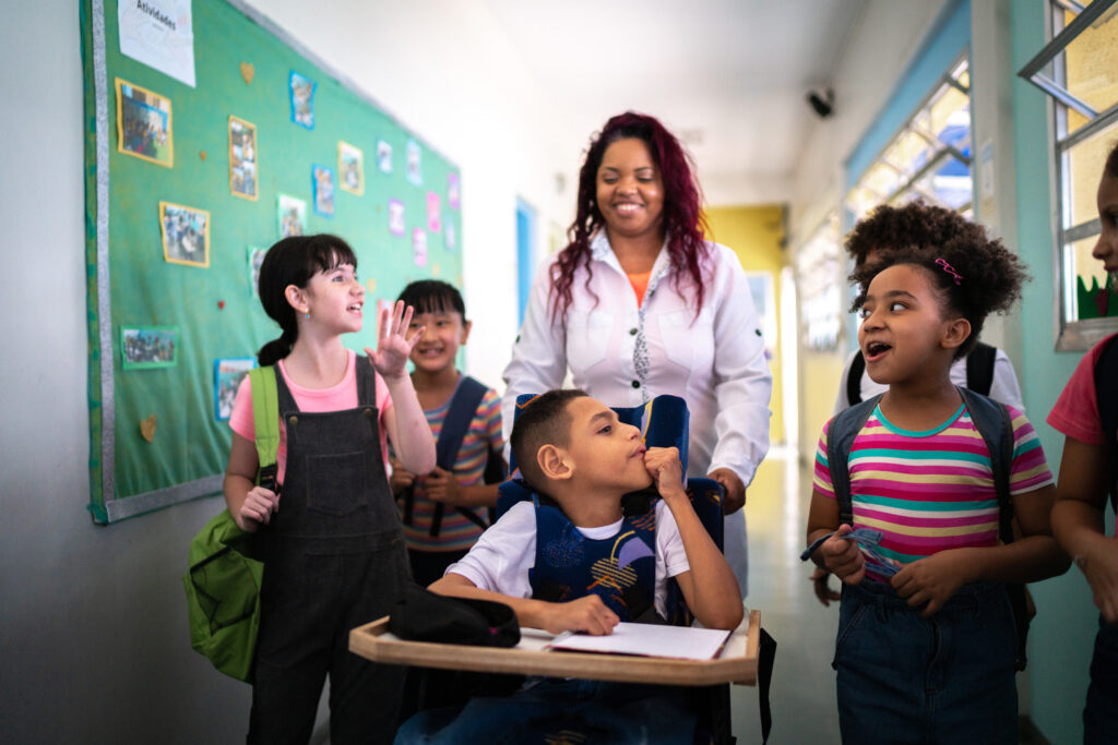 Teacher and students walking in the corridor at school - including a person with special needs