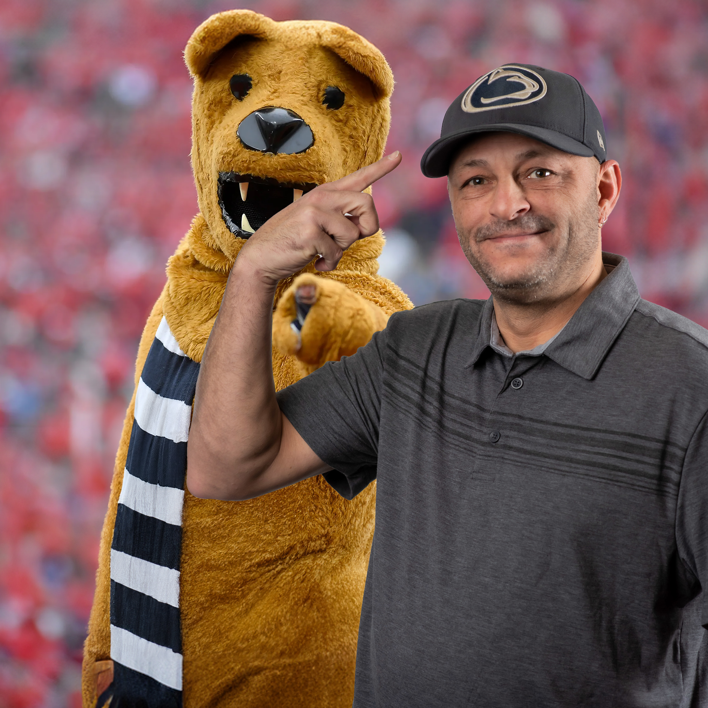 Brian Green pointing at Penn State Lions hat with mascot behind him