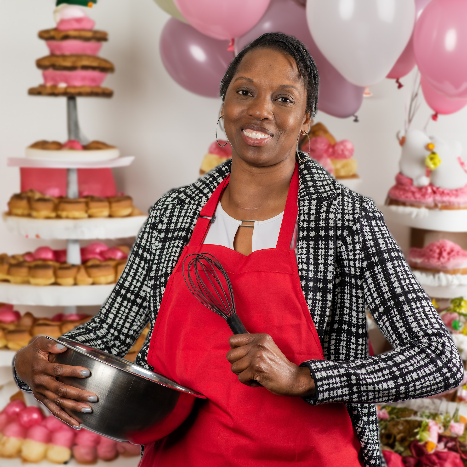 Michelle Kennedy posing with a bowl and whisk with cupcake towers and balloons in the background