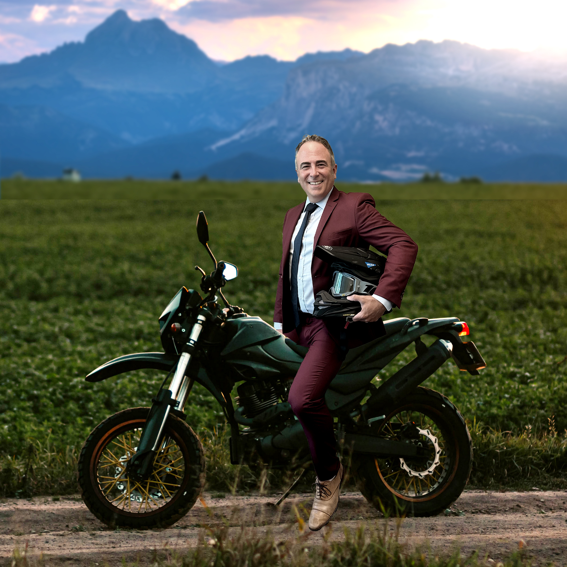 Dr. Timothy Purnell fun photo posing on a motorcycle holding helmet in front of mountains