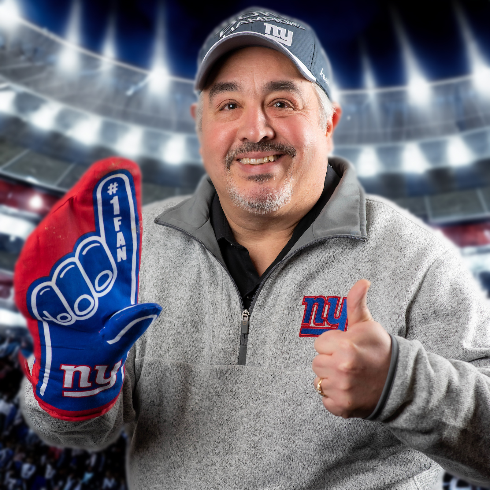 Lou Schimenti posing in NJ Giants gear holding a foam finger and MetLife stadium in the background