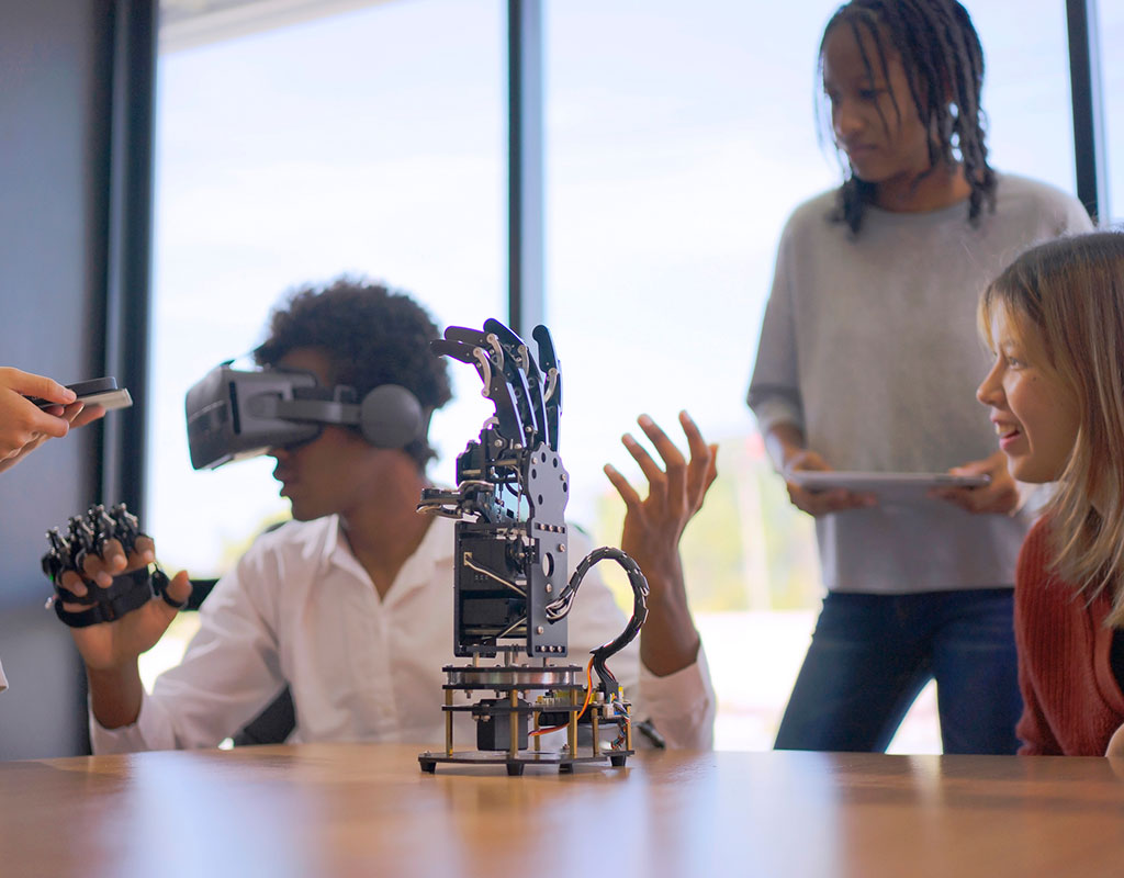 high school students wearing virtual reality glasses operating a robot hand