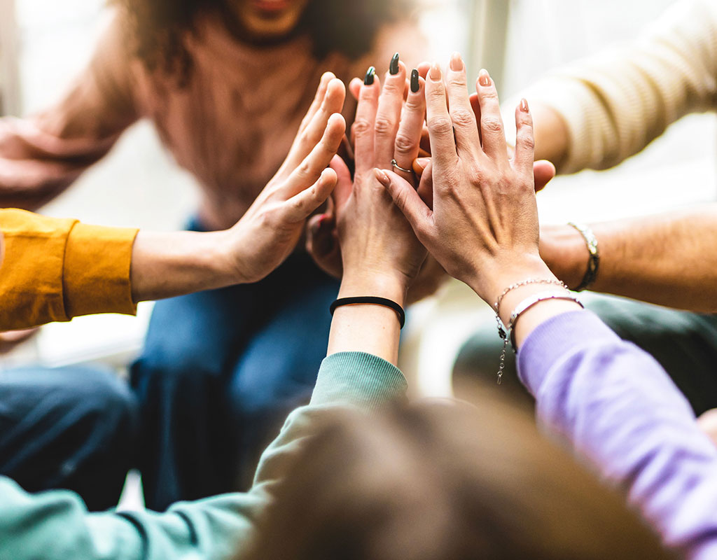 close up of a circle of adults hands high-fiving