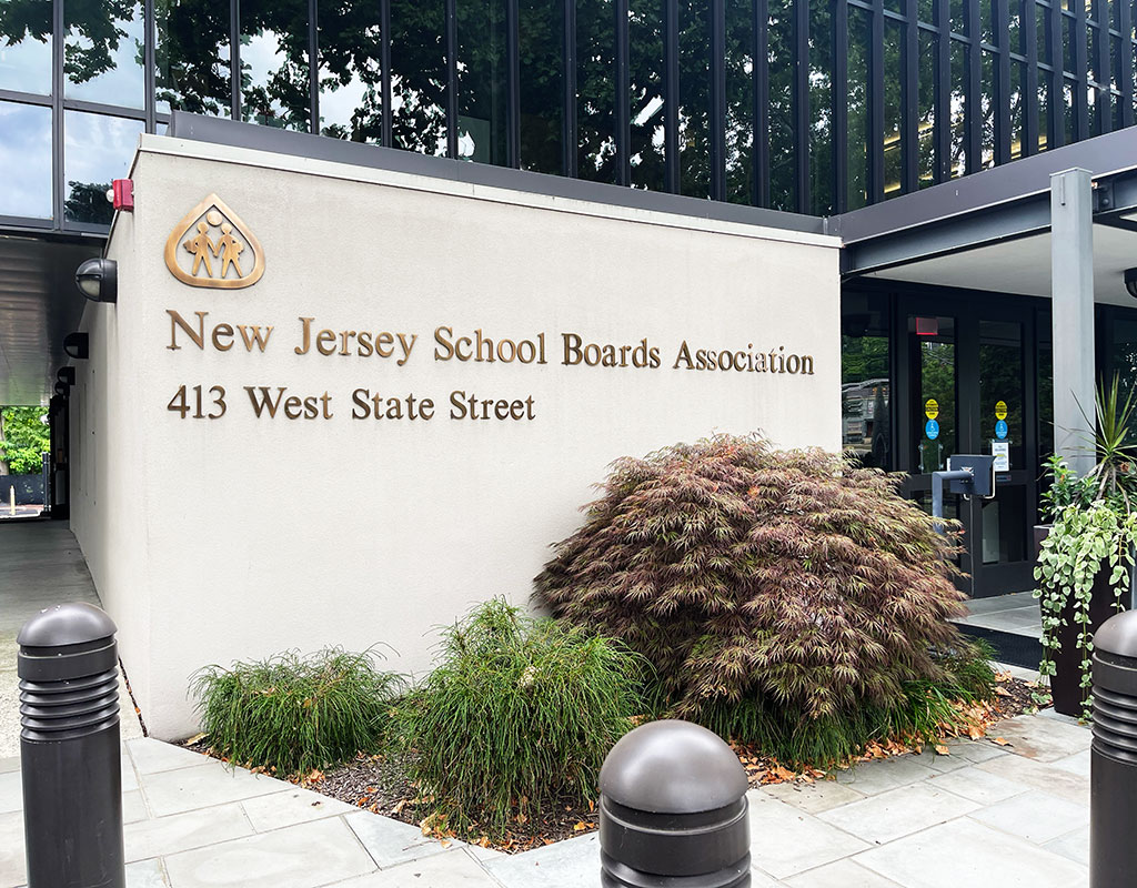 Front exterior of NJSBA headquarters zoomed in on the sign that says New Jersey School Boards Association, the address and lanscaping