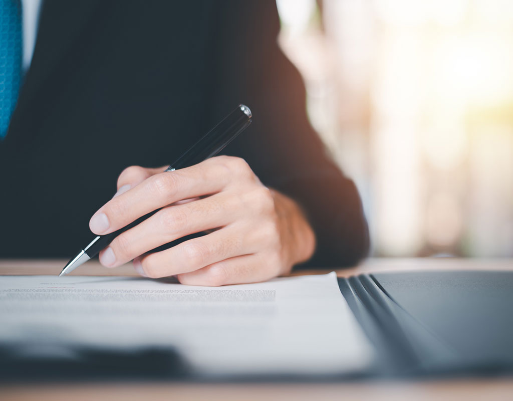 Closeup of a person signing a legal document