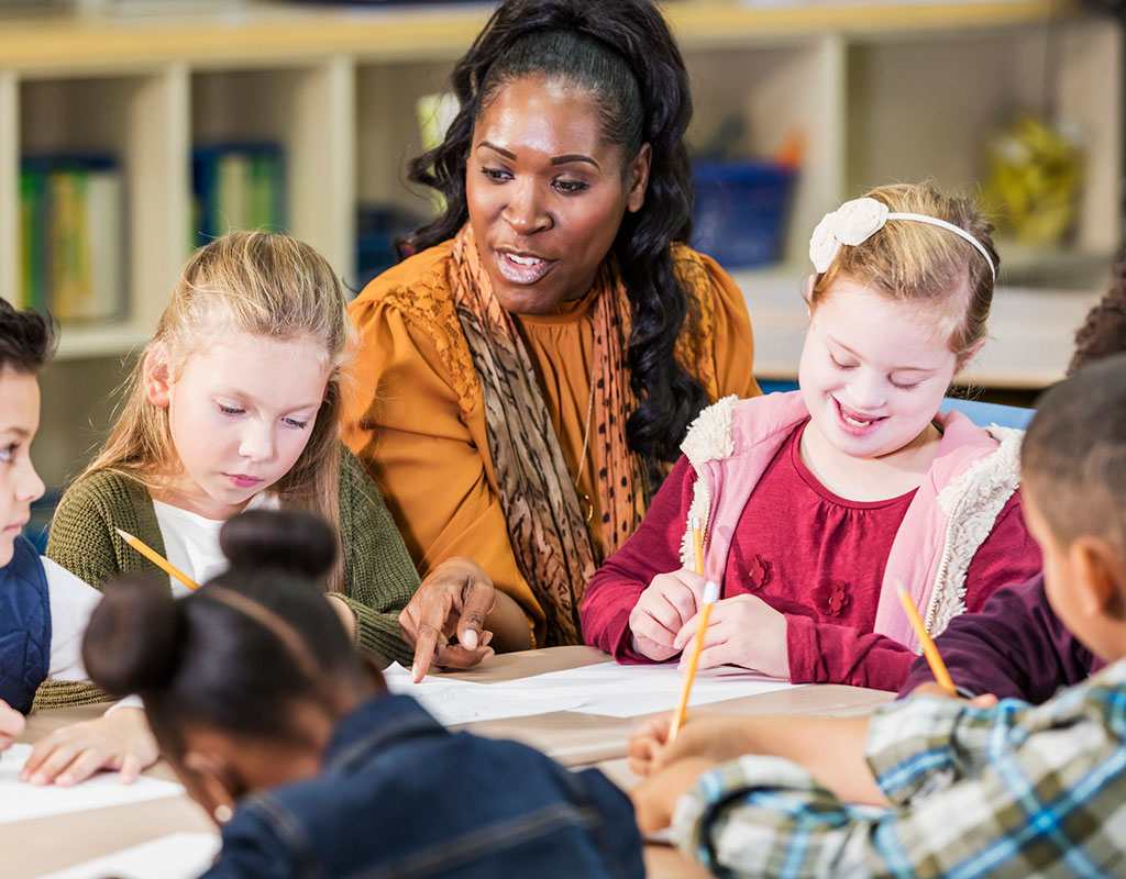 Special education students sitting around a table with a teacher writing