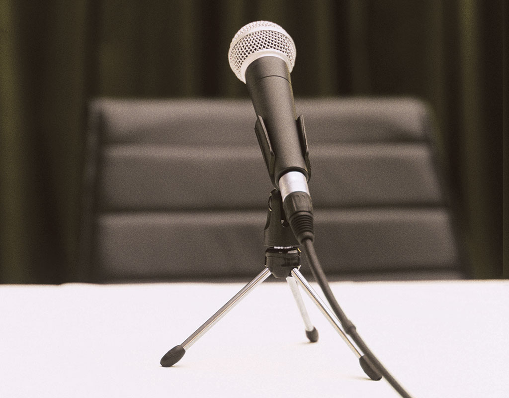 zoomed in photo of a microphone sitting on a table with an empty chair behind it