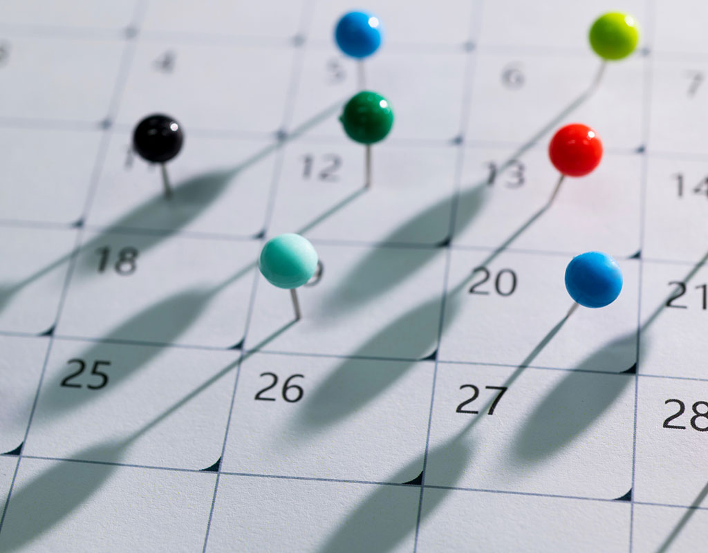 Closeup of colored pins on a calendar.