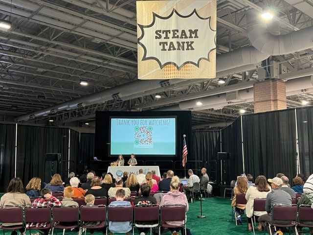 A crowd at NJSBA’s Workshop watches students present their STEAM Tank projects.